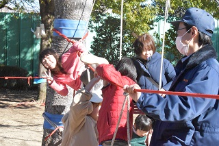 木と木の間に張ったロープで遊ぶ子ども達