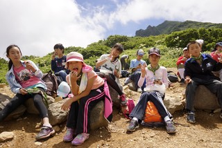 磐梯山の山腹で休憩する子どもたちの写真