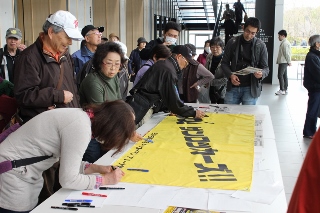 プロバスケットボールチーム・サンロッカーズ東京の横断幕に応援メッセージを書き込む市民の方の写真