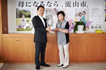 義援金を持つ国府田さんと井崎市長の写真