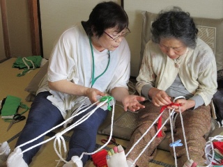 足に布を引っ掛けて編み進める参加者の写真