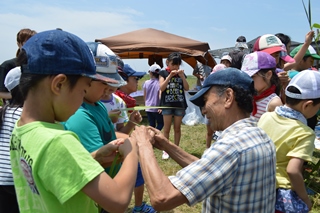 茎飛ばしのコツを教わる子どもの写真