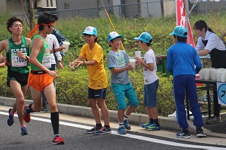 写真：ランナーに飲み物を渡す児童たち