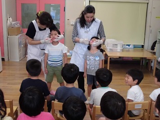 写真：歯の染め出しの披露する先生と子どもたち