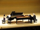 写真：2台のグランドピアノを向かい合わせに演奏をするパスカル夫妻