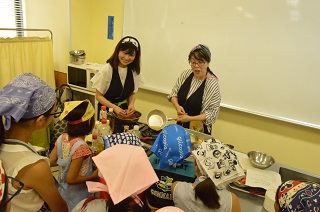 写真：調理方法を教える大瀬さんと川浦さん
