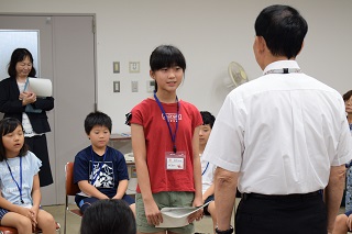 写真：作品集を手渡す田内さん