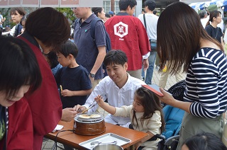 写真：せんべい焼きを体験する松本さんご家族