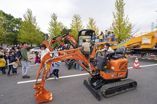 写真：働く車コーナーで記念撮影をする家族