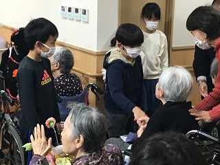 写真：お年寄り握手する児童