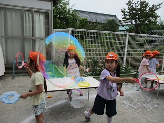 子どもがしゃぼん玉を作り大きなしゃぼん玉が出来上がる