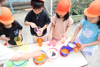 子ども達がカップに色々な色水を足してかき混ぜている