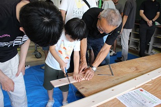 のこぎりで板を切る小学生