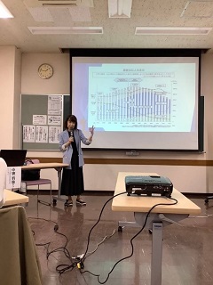 第1回の講師、中野洋恵さんがグラフが映し出されたスクリーンの横でマイクを持って話す写真