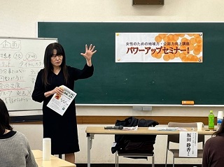第2回の講師、坂田静香さんが黒板の横で左手を挙げて話している写真
