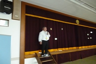 舞台の上で館長があいさつをする様子の写真