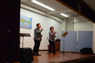 武山伸一さんとそのお父さまが舞台上で歌う様子の写真
