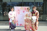 祝祭と書かれたパネルの前でポーズをとる振袖姿の3人の女性の写真