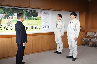 井崎市長と派遣される職員2人が向き合って立っている様子の写真