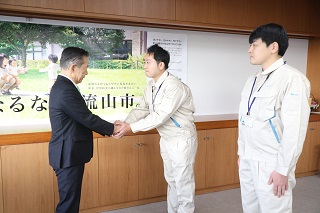 握手をする井崎市長と派遣される市職員の写真