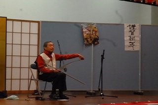 舞台上で西洋のこぎりを弓で弾いているのこ木本さんの写真