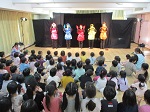 様々な色の衣装を着た人形劇団の皆さんが舞台で歌っています。