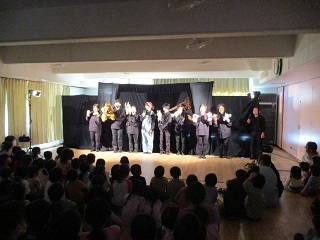 ヤギなどの様々な人形を手に劇団の皆さんが舞台に並んでいる写真