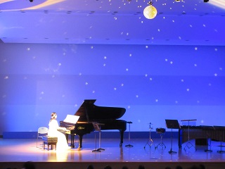 夜空のイメージを背景にピアノを演奏している様子