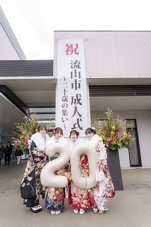 流山市成人式と書かれた立て看板の前で並んでポーズをとる振袖姿の4人の女性の写真