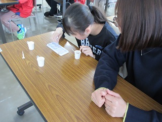 イクラのつぶつぶを作る子とそれを見守る保護者の様子