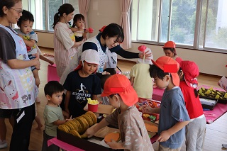 年長クラスの子ども達が1歳児クラスの子にお店屋さんの品物を売っている