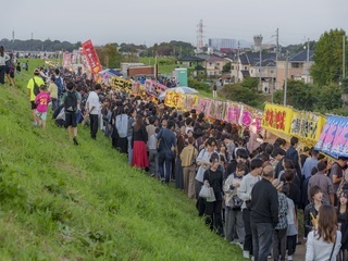 屋台と人でにぎわう土手沿いの写真