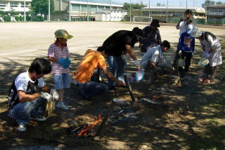 地中に埋めた缶の上で火を燃やす様子の写真