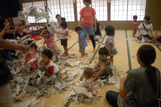 新聞をちぎって遊んでいる子どもたちの写真