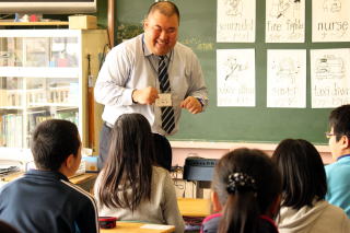 中学校の先生が小学校で出前授業をしている写真