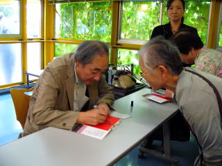 著書にサインをする佐野さんの写真