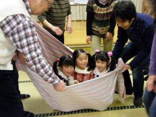 毛布のブランコで遊ぶ子どもたちの写真