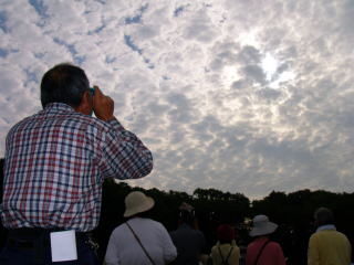 薄曇りの中、雲の合間から日食を観察