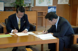 協定書にサインをする井崎市長と村田社長