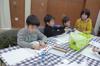 ろうそくに貼る絵を描いたり、色をぬったりする子どもたち