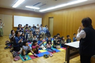 大勢の子どもの前でお話をしている写真