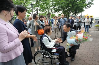 市役所の前に集まった市民の皆さんと握手を交わす市長の写真