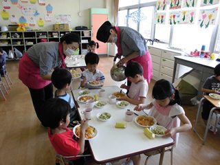 給食を食べる先生と子どもたちの写真