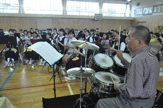 ドラムを演奏して見せる猪俣さんの写真