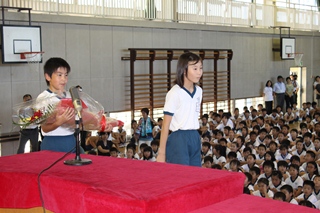 国体選手に花束を贈呈する児童の写真