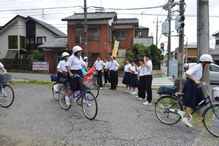 交差点で下校する生徒に声掛けを行う自転車マナーアップ隊の写真