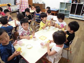 班になってとうもろこしを食べる子どもたちの写真