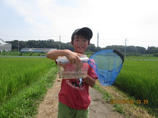 虫を捕まえて満面の笑みの子どもの写真