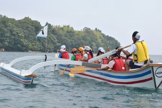 大型カヌーで沖に漕ぎ出す写真