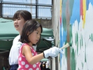壁に色を塗る小学生の写真